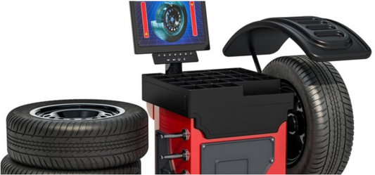 Wheel balancer machine with digital display alongside car tires in a professional automotive workshop
